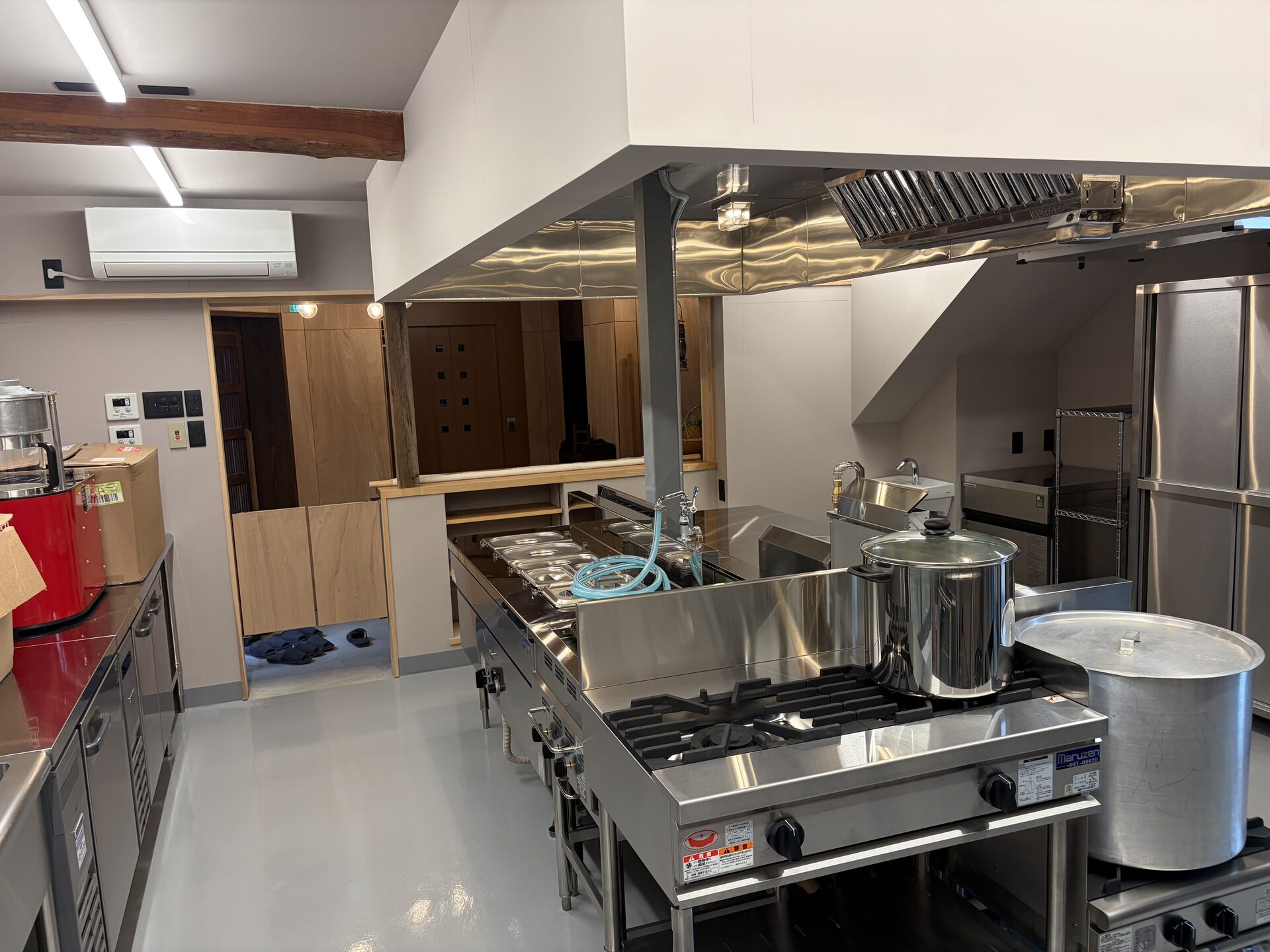 Commercial kitchen cooking area with gas burners, stock pots, and stainless steel surfaces