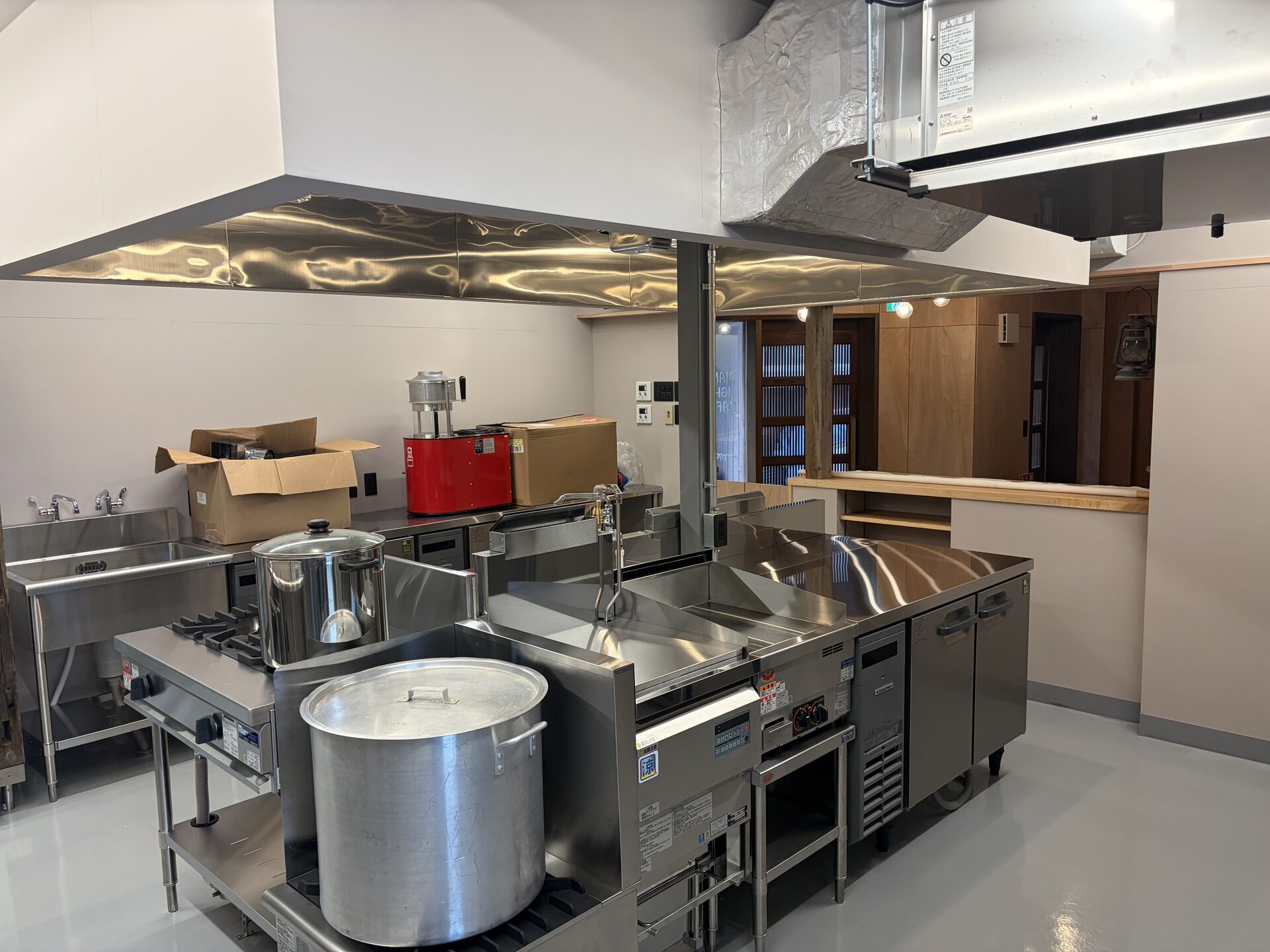 Completed commercial kitchen with stainless steel sinks, counters, and cooking equipment