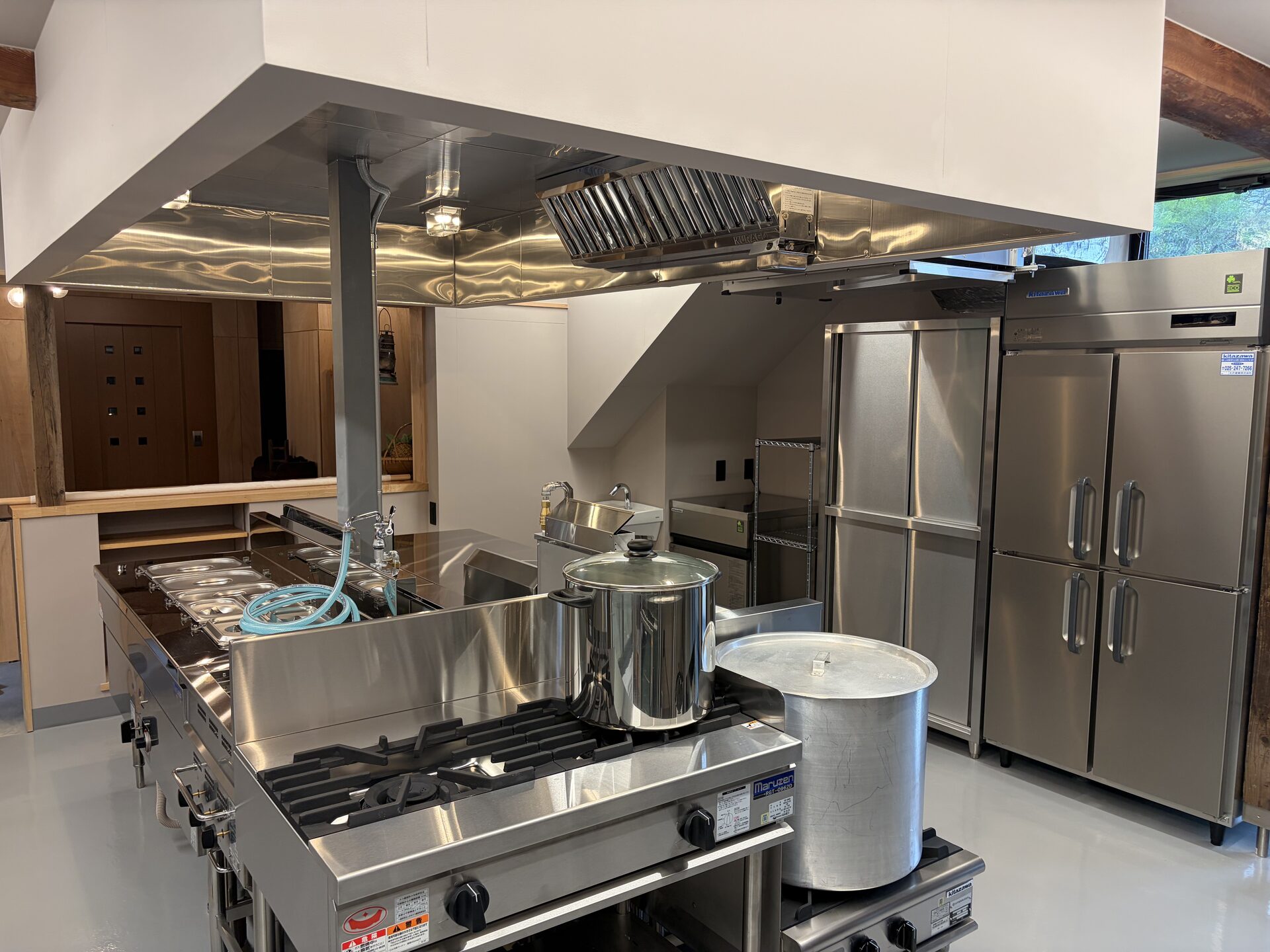 Professional gas range, ventilation hood, and upright refrigerators in the finished kitchen