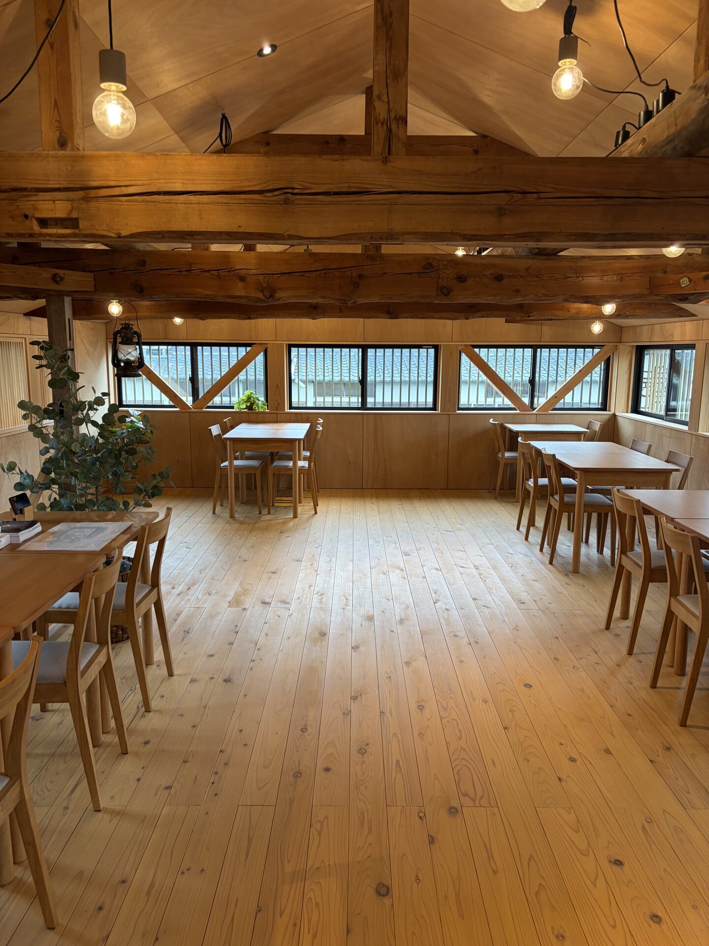 Wide view of the restored kominka dining room with exposed timber beams and wood flooring