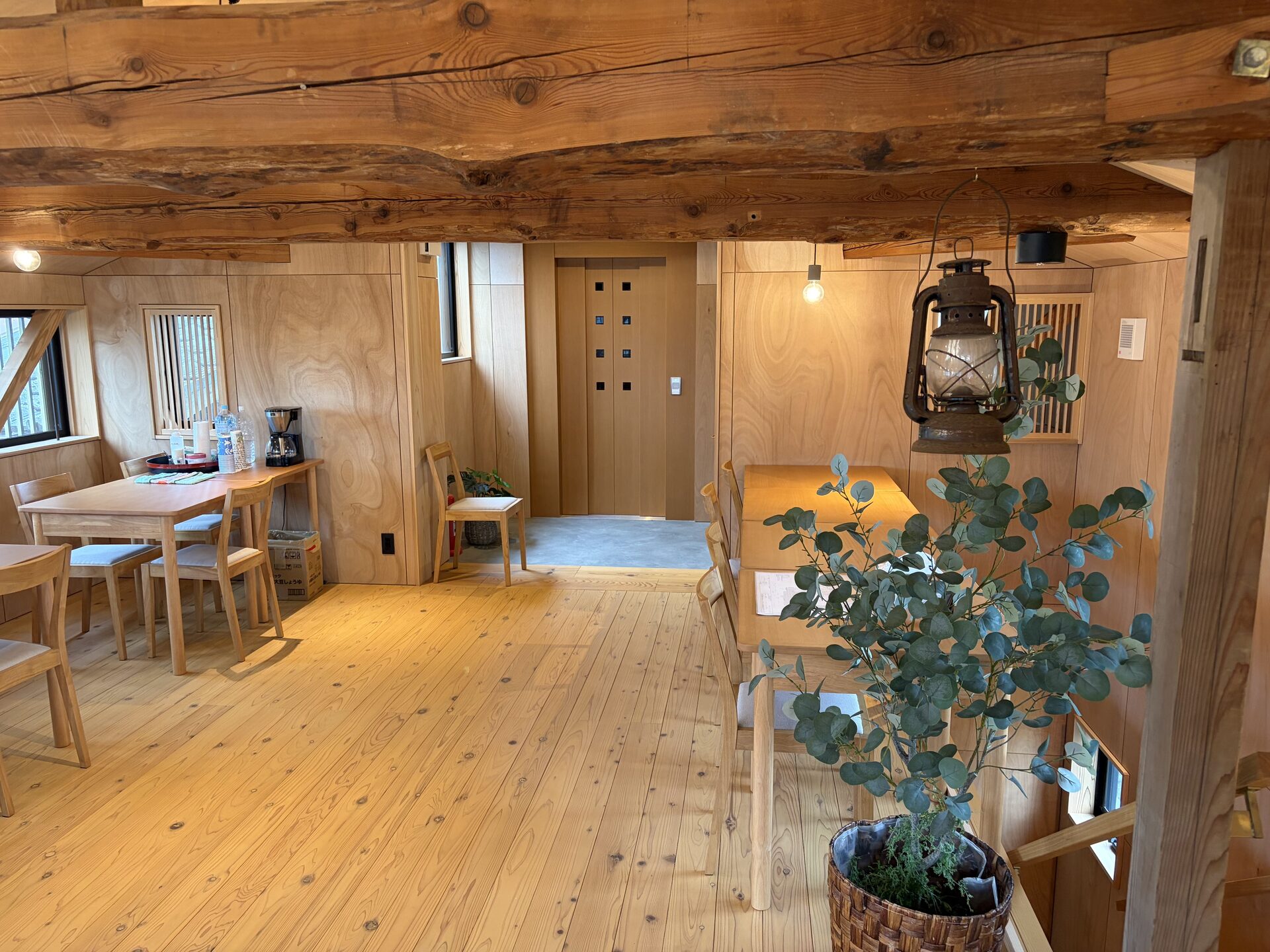 Restored Japanese kominka interior featuring original wooden posts, beams, and modern lighting